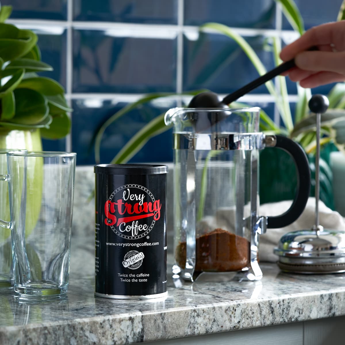 a tin of very strong coffee and a cafetiere with ground very strong coffee in it.