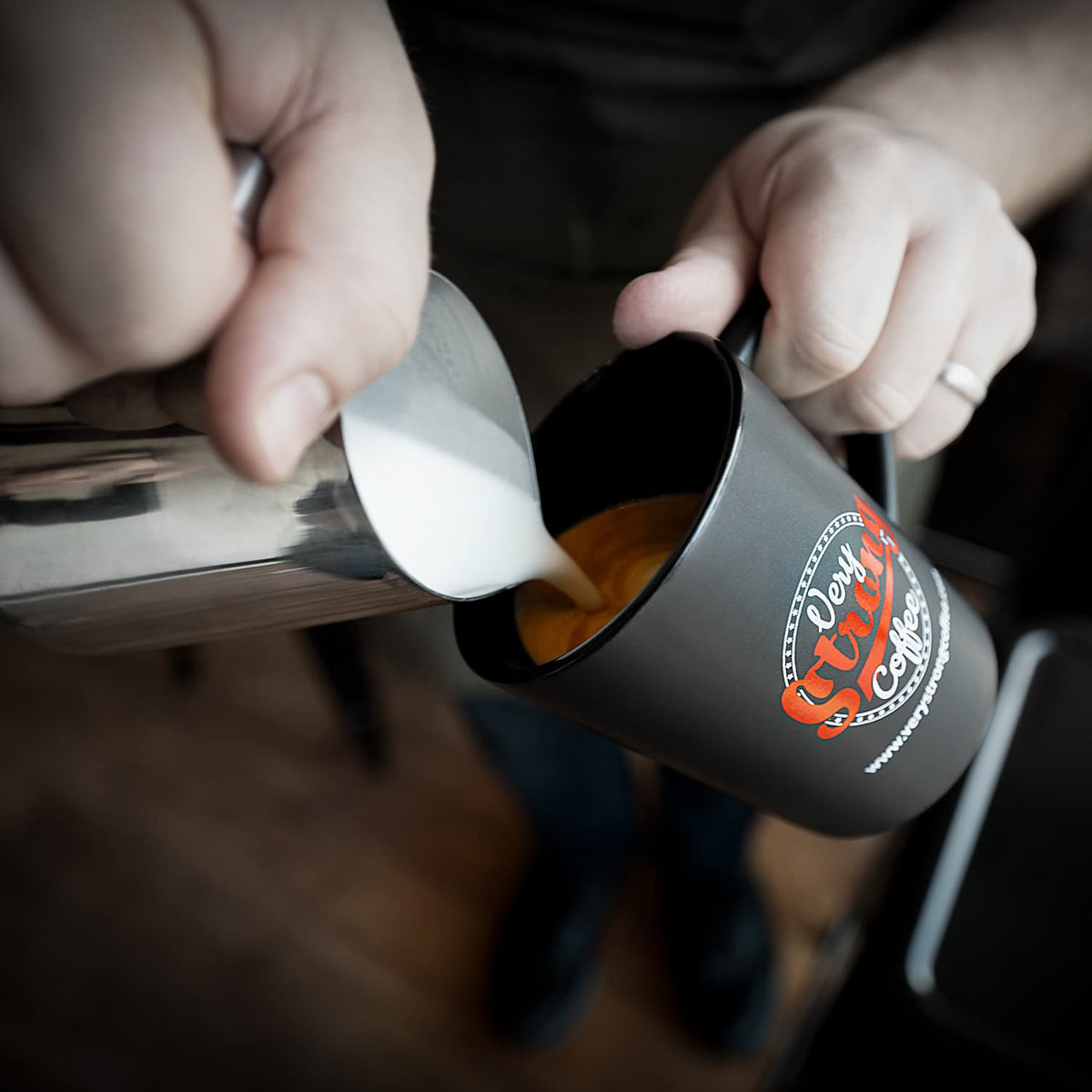 very strong coffee in a mug with the very strong coffee logo on it and milk being poured in