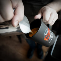 very strong coffee in a mug with the very strong coffee logo on it and milk being poured in